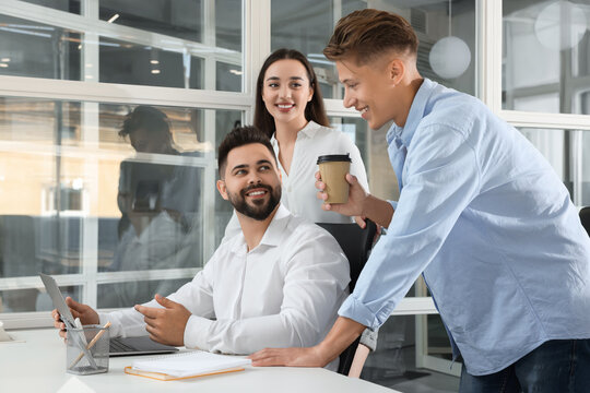 Colleagues Working Together In Open Plan Office