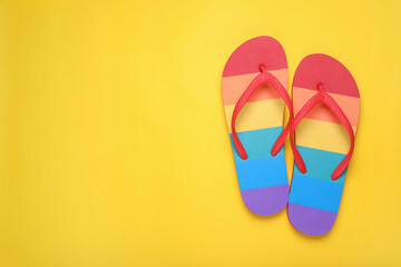 Rainbow flip flops on yellow background, flat lay with space for text. LGBT pride