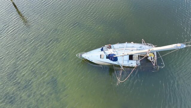 Capsized sunken sailing boat left forsaken on shallow bay waters after hurricane Ian in Manasota, Florida