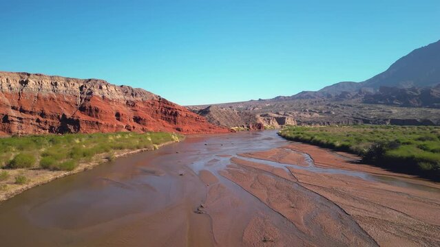 Aerial view drone flying over scenic rocky mountains and a red river landscape with a clear blue sky. Quebrada de las conchas, Cafayate, Salta, Argentina.