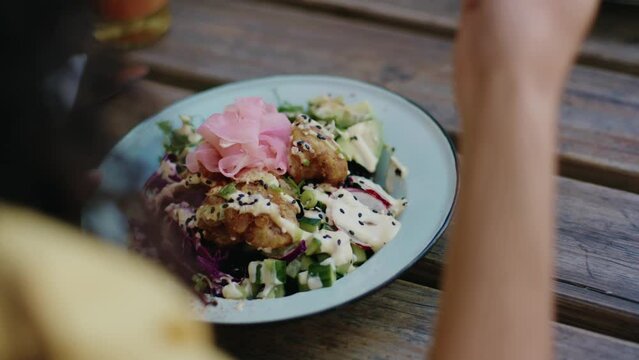 Close-up of young multiracial woman in casual clothing eating healthy food for lunch at vegan cafe