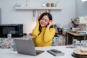 Obraz na płótnie Canvas Asian beautiful woman smiling at home in headphones . young girl listen music at home. Use technology, lifestyle concept