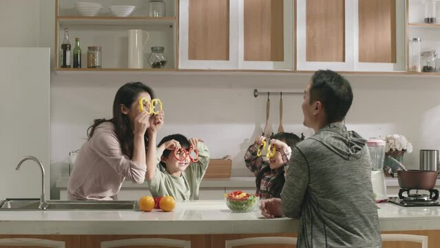 happy asian family with parents and two children having fun in kitchen at home