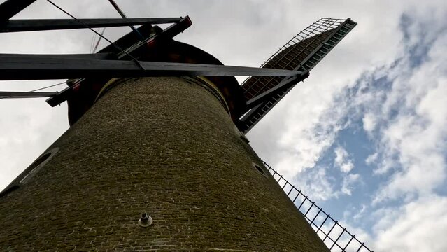 Closeup views of an iconic Dutch windmill rotating against a cloudy blue sky. Built in 1738 and 1740, to keep water out of the low-lying areas. They have been a UNESCO World Heritage Site since 1997.