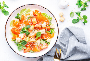 Delicious caesar salad with salmon, iceberg and lettuce, croutons, parmesan cheese and caesar dressing. White table background, top view