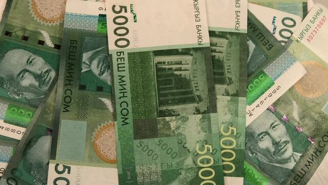 5000 som money of Kyrgyzstan close-up tracking rotate. Paper bills 5000 Kyrgyz som on table close up. Many five thousand som cash. Wealth and prosperity concept