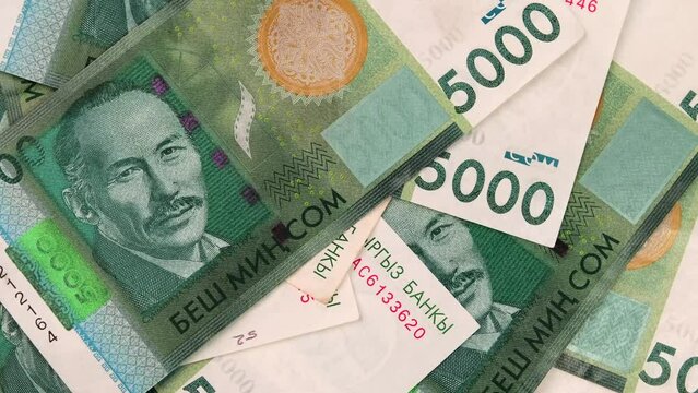 5000 Kyrgyz som bills slow rotate out on table. Five hundred value banknotes, Kyrgyzstan Republic national paper currency. Concept of making profit.