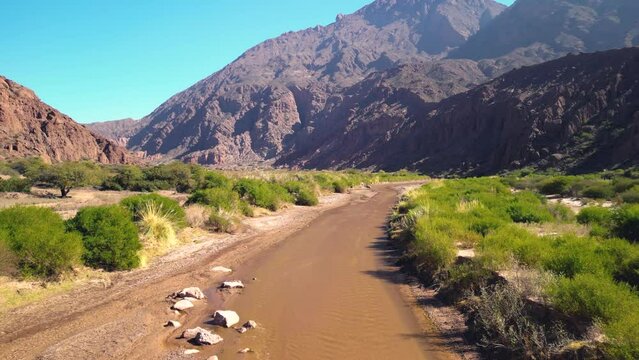 Aerial view drone flying over scenic rocky mountains and a red river landscape with a clear blue sky. Quebrada de las conchas, Cafayate, Salta, Argentina.