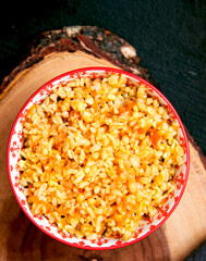 Easy bulgur pilaf in a ceramic bowl on a dark background close-up. Vegan food