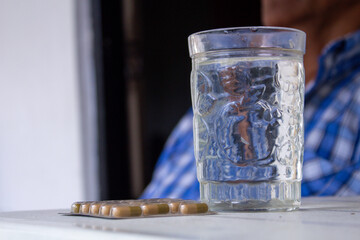 adult man taking some medicinal pills with a glass of water