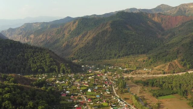 Aerial view of beautiful panorama mountain pass and traditional village of Arkit of colorful rooftops of houses on sunny summer day. Calm beauty of living in nature outdoors.