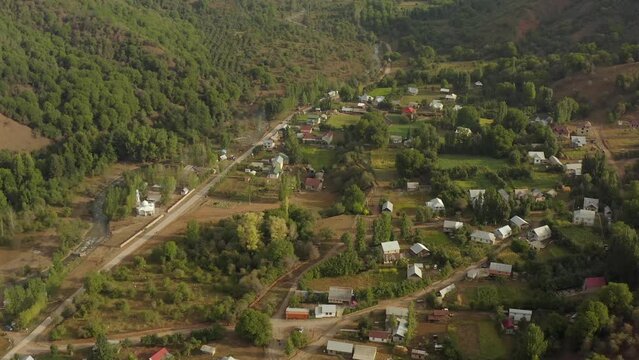 Aerial tracking shot landscape of mountains traditional Arkit scenic village in Kyrgyzstan, drone video. Traditional village Central Asia on sunny summer day. Settlement located in highlands.