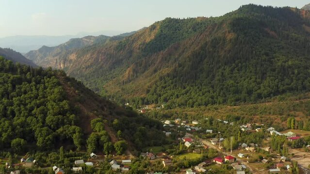 Spectacular aerial shot beautiful traditional village Arkit with small houses colorful roofs. Mountains in Central Asia panorama and village on sunny summer day.
