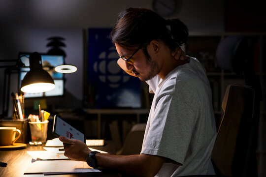 Asian man graphic designer working on computer drawing sketches logo design. Young Asian businessman looking serious and stressed while using laptop to work from home. - Powered by Adobe