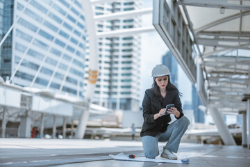 Expert female architect reviews Skytrain site, cross referencing blueprint for project approval.