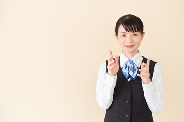 説明するベストにリボンタイの制服を着た、受付業務、事務業務の女性