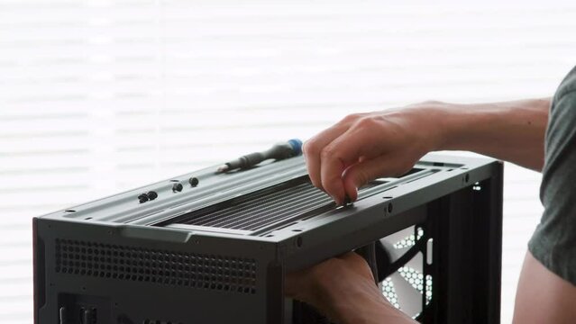 Man attaching a radiator to a computer case. Liquid cooling. Computer hardware