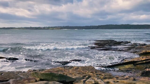 HD Video -View at the entry to Botany Bay in Sydney Metropolitan area with waves splashing on the rocky beach at Kurnell in the foreground, and La Perouse Point in the background in NSW, Australia.