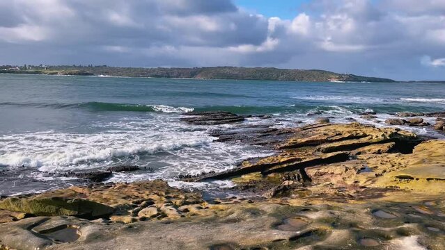 HD Video-Panning view at the entry to Botany Bay in Sydney Metropolitan area with waves splashing on the rocky beach at Kurnell in the foreground, and La Perouse hills in the background-NSW, Australia