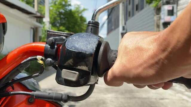 Close up male driver hand on throttle handle motorcycle on road daytime urban city. Transportation concept