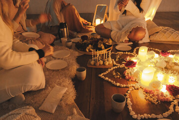 Beautiful women enjoing delicious treats with warm tea in a cosy candle light fille room by the...