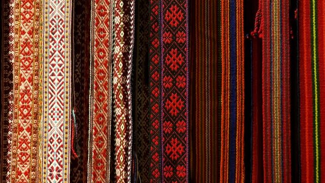 Vintage hand-woven wool garters in bright traditional Latvian regional colors hanging on the wall