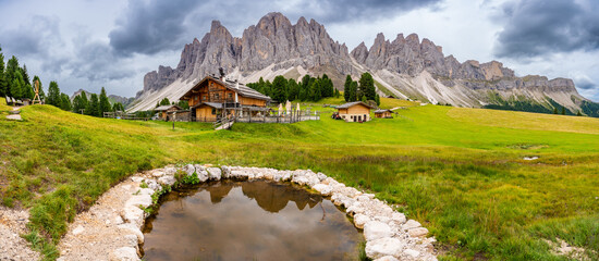 Dolomite landscape in Puez Odle Nature Park - view from alpine plateau with wooden houses and green meadows