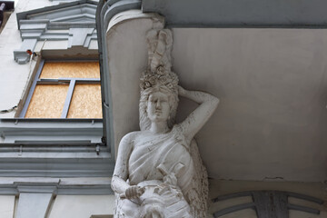 Support for a balcony in the form of a Greek statue. Windows sewn with wood after shelling