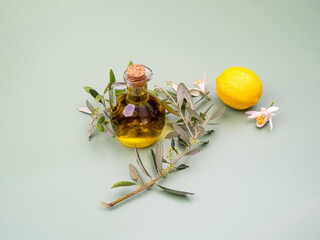 Mediterranean concept, flask with extra virgin olive oil with lemon and olive tree leaves on an olive background