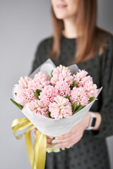 Young happy woman holding a beautiful bunch of pink hyacinths in her hands. Present for a smiles girl. Flowers bouquet.