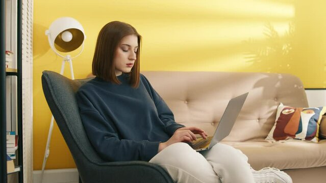 Smart woman working on laptop at home. Clever girl typing on computer keyboard. Female student learning online with gadget. Serious lady browsing internet on laptop. Study concept, 4k footage