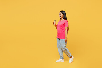Fototapeta na wymiar Full body young happy Indian woman wearing pink t-shirt casual clothes hold takeaway delivery craft paper brown cup coffee to go isolated on plain yellow background studio portrait. Lifestyle concept.