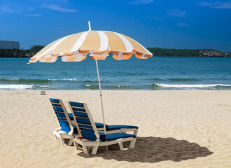 Couple sitting under a multicolored yellow umbrella stand on a sandy beach against the background...