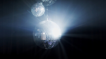 A colorful disco mirror ball illuminates the backdrop of a nightclub. The party lights up the disco ball.