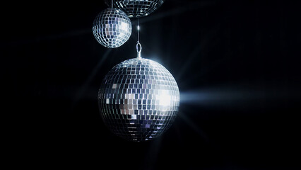 A colorful disco mirror ball illuminates the backdrop of a nightclub. The party lights up the disco...