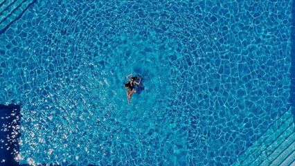 View from above. The couple have fun in the pool. A young attractive couple is relaxing in the pool. Enjoying each other's company.