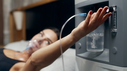 Portrait of a sick young woman who uses an oxygen concentrator and an inhaler for treatment at...