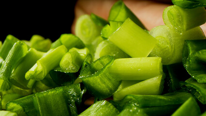 Slicing, cooking process, tasty and bright image, sharp knife, slicing green onions, dark background on the background.