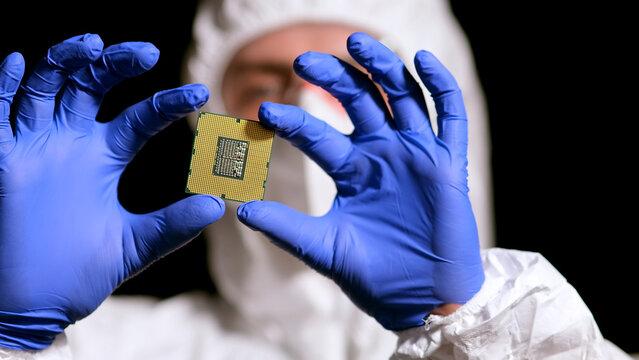 Engineer man in sterile suit is holding Microchip with symbols in modern design factory , futuristic and artificial intelligence concept
