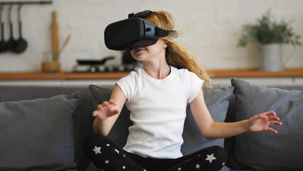 Beautiful girl in a virtual reality headset. Augmented reality. Happy cute girl touching something using modern 3d vr glasses indoors. Plays with VR glasses