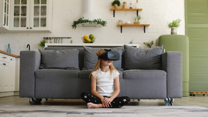 Beautiful girl in a virtual reality headset. Augmented reality. Happy cute girl touching something using modern 3d vr glasses indoors. Plays with VR glasses