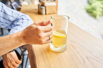 Cup of ginger root tea with lemon, honey and mint on a wooden table and High-mountain river in the background. Walk in the mountains and relax in a cozy cafe. Hiking on a day off - 635759231