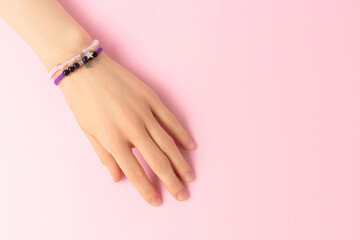 Female hand with a macrame bracelets on it on a pink baclground.