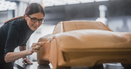 Close Up of a Female Automotive Designer Trimming a 3D Clay Model of a New Production Car....