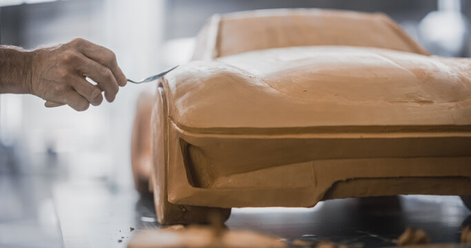 Close Up Of A Specialist Modeler Working On Vehicle Production First Step, Creating A Miniature Scale 3D Car Model Out Of Clay. Anonymous Man Carefully Trimming The Surface Of A Concept Vehicle