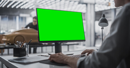 Automotive Designer Working on a Desktop Computer with Green Screen Mock Up Display. Digital Artist...