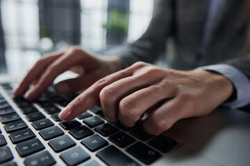 Close-up of male hands using laptop at office