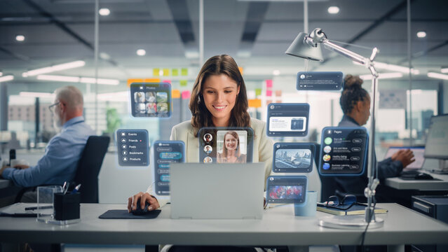 Young Businesswoman Using Laptop Computer in Office with Colleagues. Stylish Social Media Manager Smiling, Working Online Marketing Projects. VFX Hologram Edit Visualizing Social Network With Friends. - Powered by Adobe
