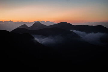 Obraz premium A flawless sunset paints the backdrop behind the silhouetted black mountains.