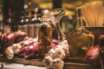 Display of mediterranian produce, warmly lit in the evening. Garlic, Onions, Olive Oil.